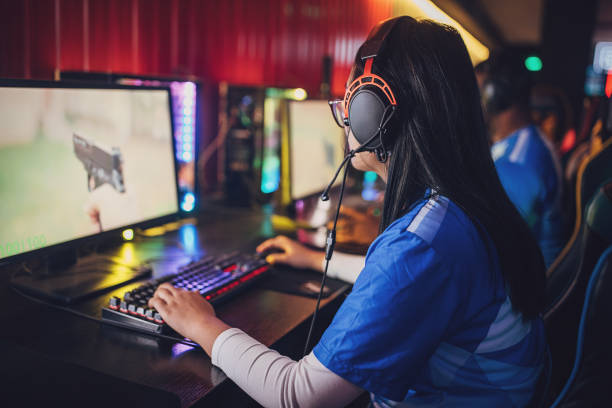 Professional eSports Young Asian Woman Gamer focused while playing video game with her team